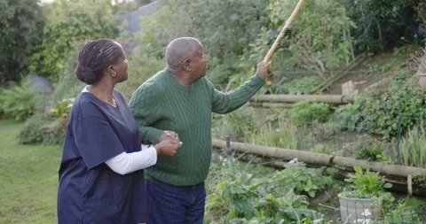 Senior man pointing cane, signaling path, caregiver in scrubs supporting and Stock Footage 345508995