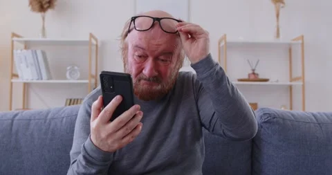 Senior man with poor eyesight having problem reading message on his mobile phone Stock Footage 344984804