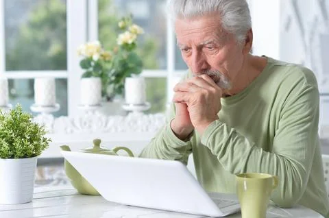 Senior man posing and using laptop at home Foto stock