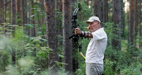 Senior man practicing archery with compound bow in forest Stock Footage 340998392