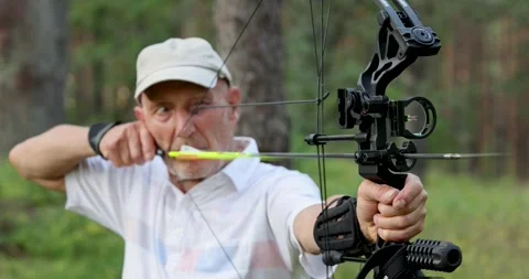 Senior man practicing archery with compound bow in forest Stock Footage 340998623