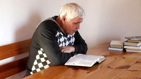 Senior man praying, reading an old Bible in his hands. Stock Footage 165172796