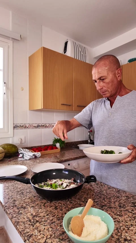 Senior man preparing a delicious and healthy vegetarian meal at home Stock Footage 344175364