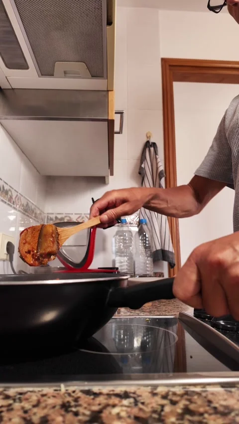 Senior man preparing a healthy meal, stirring diced eggplant with tomato sauce Stock Footage 344537693