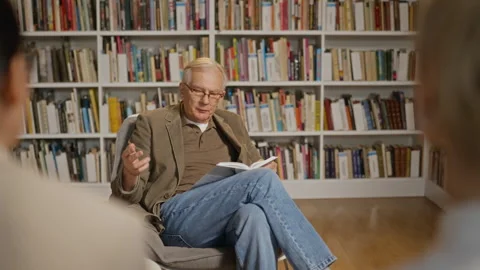 Senior Man Presenting Book and Speaking to Audience in Library Stock Footage 338055085