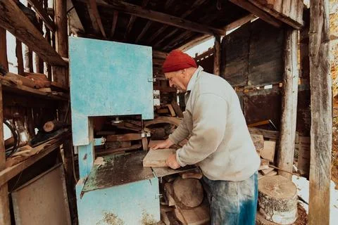A senior man processing wood on a machine in an outdoor workshop. Foto stock