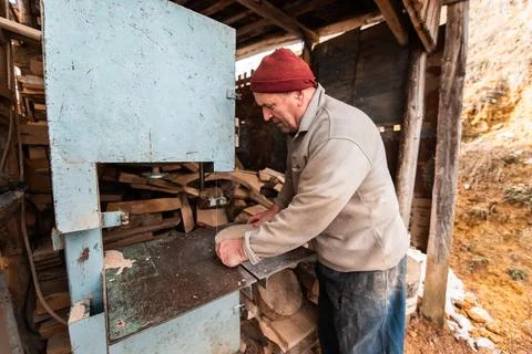 A senior man processing wood on a machine in an outdoor workshop. Foto stock