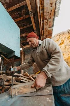 A senior man processing wood on a machine in an outdoor workshop. Foto stock