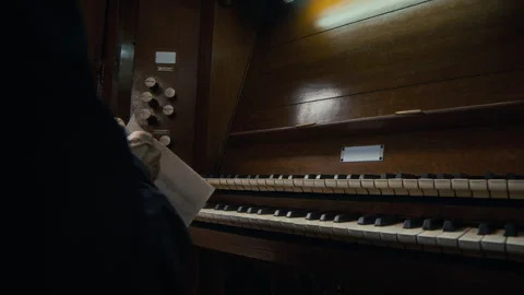 Senior Man Pulling out Stop Knobs of Organ and Opening Sheet Music Video stock 286110606