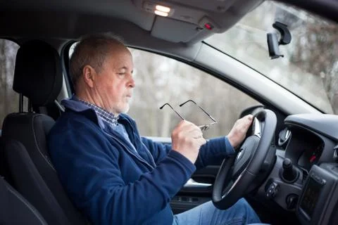 Senior man putting on glasses before driving, his eyesight is not good, safety Stock Photos