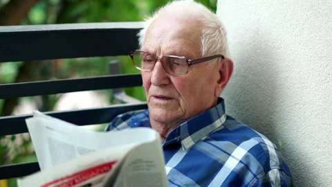 Senior man reading newspaper while sitting on the balcony 스톡 동영상 93761766