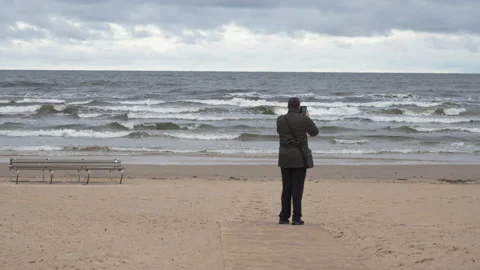 Senior man recording video on empty Jurmala beach at Baltic Sea Latvia Stock Footage 325974366