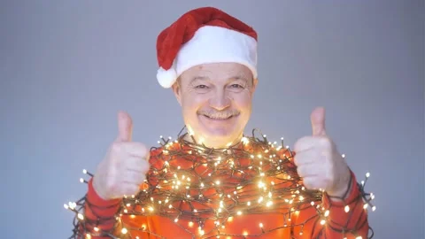 Senior man in red christmas hat wrapped in garland. Stock Footage 169716351