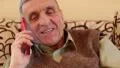 Senior man with red smartphone speaks and smiles HD Footage