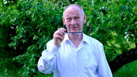 Senior man removing and putting on glasses while smiling at camera near apple Stock Footage 345338912