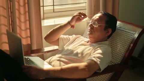 Senior man removing glasses and rubbing tired eyes after long hours of computer Stock Footage 343835155