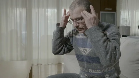 Senior man rubbing his temples suffering from intense headache at home Stock Footage 88400436
