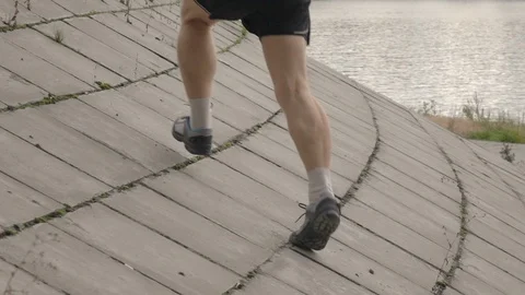 Senior man running up on flagging downhill. Slow motion macro shot of male legs Vídeos de archivo 117291937