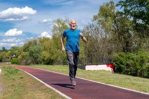 Senior man running on the jogging track on the quay. Stock Photos