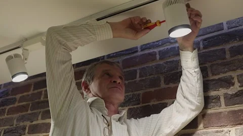Senior man screws spotlight on ceiling. Slow motion Stock Footage 276369318