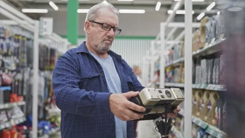 A senior man is in a shop choosing a compressor for his car. A grey-haired Stock Footage 252080413