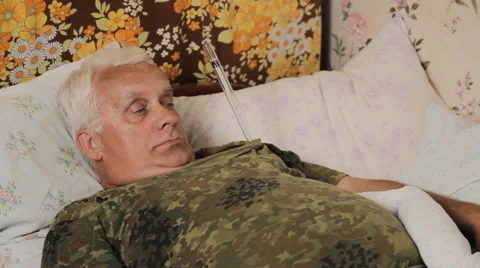 Senior man sick in bed with a huge thermometer. Funny thermometer under his arm Stock Footage 64772031
