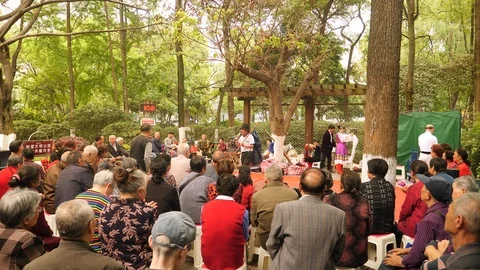 Senior man singing for audience of elder citizens in park, China. Stock Footage 112259358