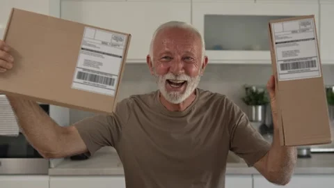 Senior man sit at home hold post package delivery present or order 스톡 동영상 250296472