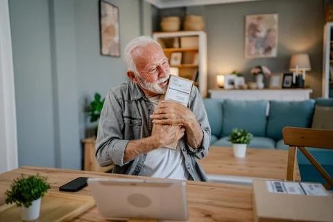 Senior man sit at home hold post package delivery present or order Stock Photos