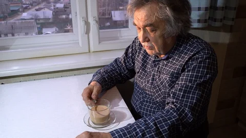 Senior man sits at a table and drinks tea with milk from a glass Cup. Stock Footage 126855685