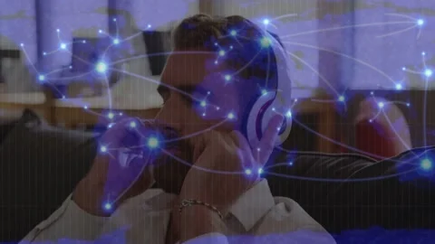 Senior man sitting on couch placing headphones testing tech as blue network 库存影片 332566221