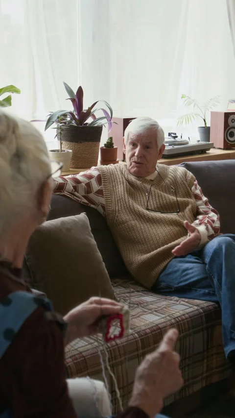 Senior Man Sitting on Couch, Talking with Woman Knitting in Retirement Home Video stock 304027982