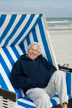 A senior man sitting on a hooded beach chair Stock Photos