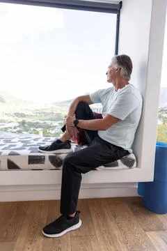 Senior man sitting on patterned window bench gazing at valley with blue foam Stock Photos