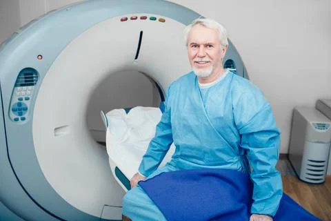 Senior man sitting on scanner table. waiting for CT scan Foto stock