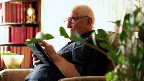 Senior man sitting with tablet on sofa at home Stock Footage 100161902
