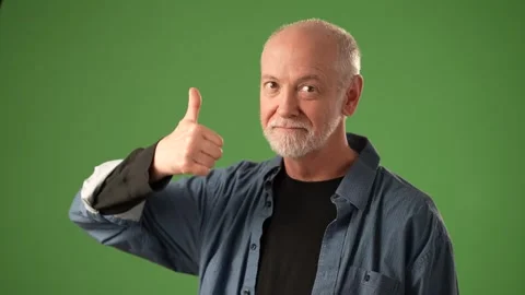 Senior Man Smiling and Gesturing With Hand Against a Green Background Stock Footage 305569435