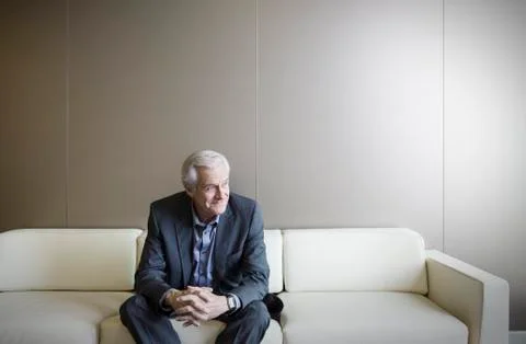 Senior man on sofa looking away Stock Photos