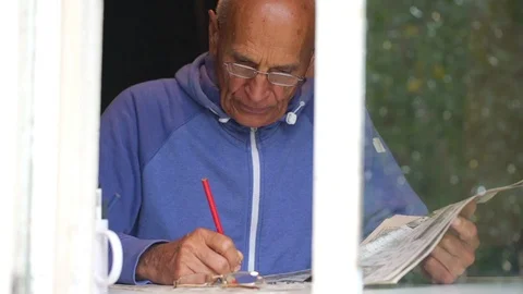 Senior man solves crossword on window sill slow motion Video stock 119017319