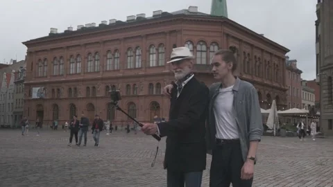 Senior man with son makes selfie with smartphone on square Stock Footage 136740909