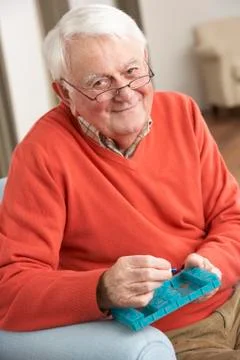 Senior Man Sorting Medication Using Organiser At Home Stock Photos