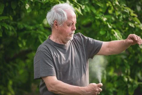 Senior man spraying or using repellent against kind of insects, mosquitoes and Stock Photos