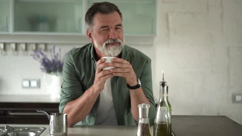 Senior man standing in kitchen drinking mug of coffee, spending time alone Stock Footage 189800421