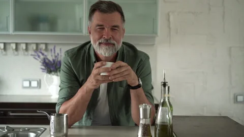 Senior man standing in kitchen drinking mug of coffee, spending time alone Stock Footage 189801090