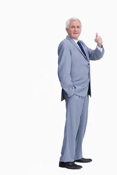 Senior man standing in studio wearing light gray suit and dark tie, giving Stock Photos