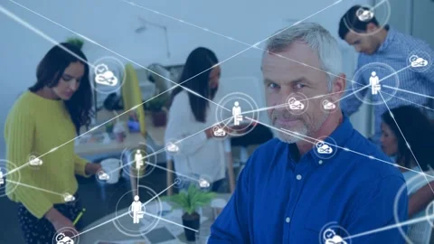 Senior man standing at table sparking network icons growing from single node Stock Footage 333967743