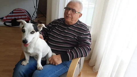 Senior man in striped pullover and blue jeans pets dog Stock Footage 110834905