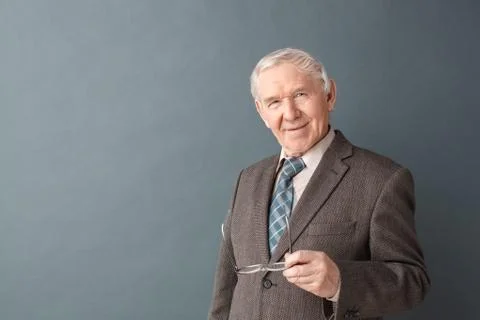 Senior man studio standing isolated on gray holding glasses looking camera Stock Photos