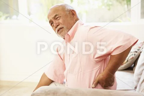 Senior man suffering from back pain at home Stock Photos