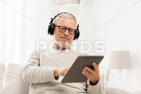 Senior man with tablet pc and headphones at home Stock Photos